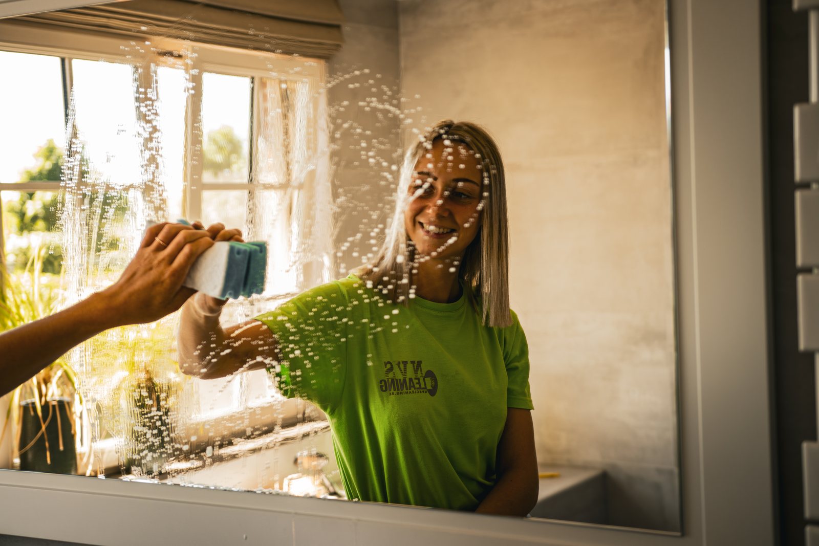 Medewerkster van NVS Cleaning wast een raam met een spons